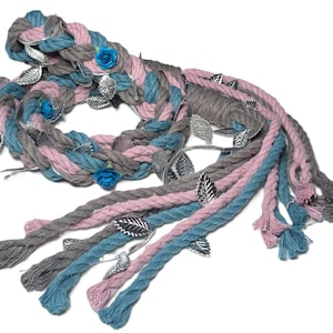 May include: Braided rope in shades of gray, pink, and teal, adorned with silver leaves and small blue fabric roses. The rope is arranged in a circular pattern with several strands extending downward.