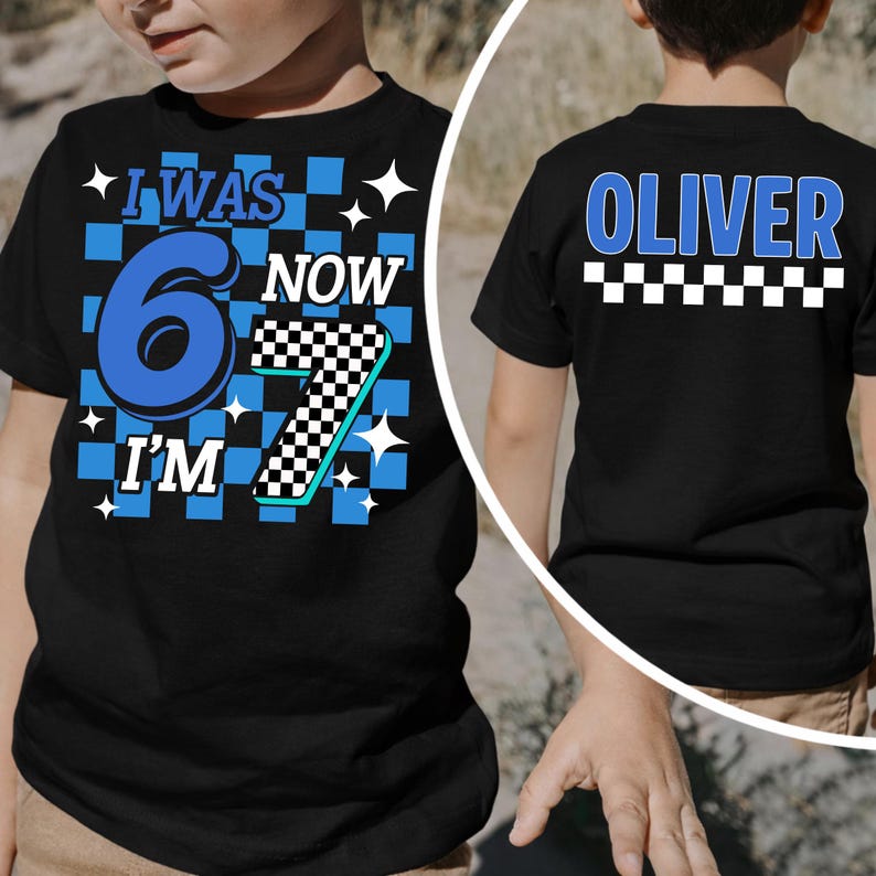 May include: Black t-shirt with the text "I WAS 6 NOW I'M 7" in blue and white, with a checkered pattern. The back of the shirt says "OLIVER" in blue. A fun birthday shirt for a child.