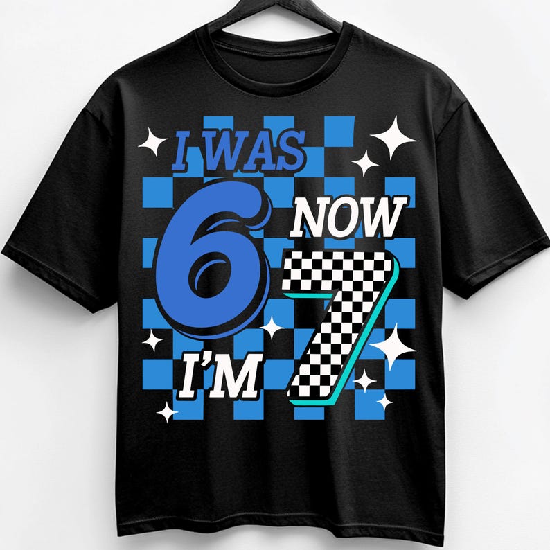 Pu&ograve; includere: T-shirt nero con la scritta "I WAS 6 NOW I'M 7". Il design presenta uno sfondo a scacchi blu e bianco con il numero 6 in blu e il numero 7 in un motivo a scacchi bianco e nero.