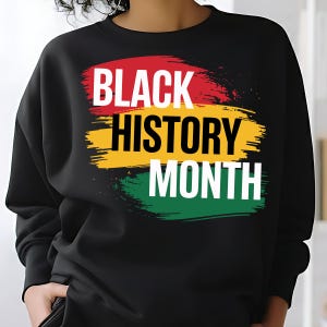 May include: Black sweatshirt with the words "BLACK HISTORY MONTH" in white lettering. The text is layered over a background of red, yellow, and green brushstrokes. The sweatshirt is black.