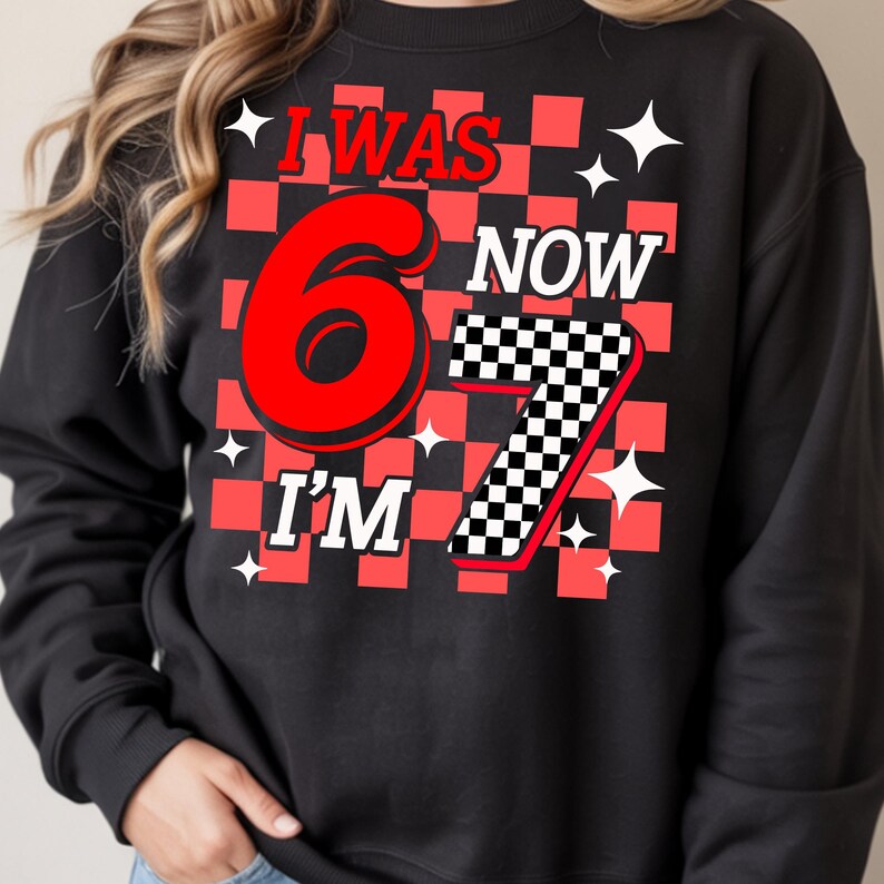 Puede incluir: Sudadera negra con un dise&ntilde;o a cuadros rojos y negros. El texto dice "I WAS 6 NOW I'M 7" en rojo y blanco. Acentos de estrellas blancas est&aacute;n dispersos alrededor del texto. Una divertida camiseta tem&aacute;tica de cumplea&ntilde;os.