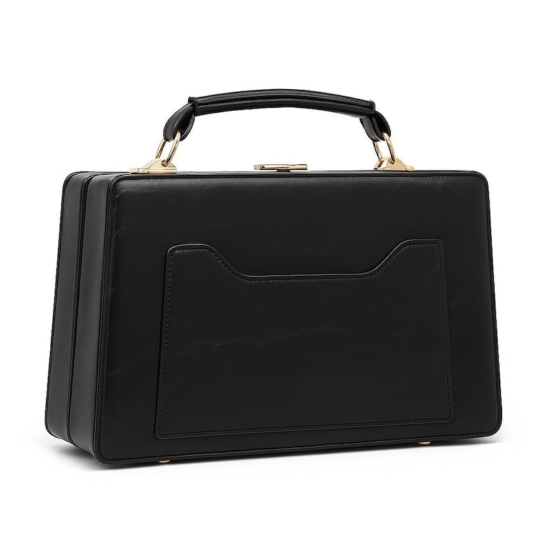 Puede incluir: Un bolso negro rectangular con asa superior y herrajes dorados. El bolso tiene un dise&ntilde;o estructurado con un bolsillo frontal y un cierre de broche. El asa es curva y est&aacute; sujeta a la bolsa con detalles met&aacute;licos dorados.