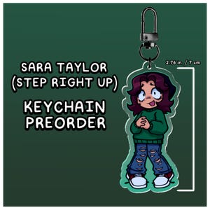 Puede incluir: Un llavero acrílico transparente con una ilustración de dibujos animados de una persona con cabello castaño, que lleva un suéter verde y jeans azules rasgados. El llavero mide 7 cm de alto y tiene un cierre de metal. El texto dice "SARA TAYLOR (STEP RIGHT UP) KEYCHAIN PREORDER."