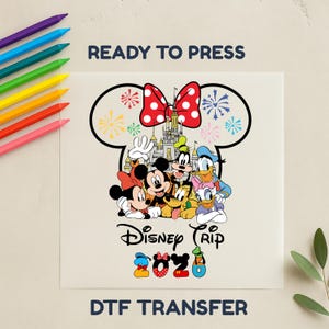 May include: DTF transfer featuring Disney characters Mickey, Minnie, Goofy, Donald, Daisy, and Pluto. The design includes a castle, fireworks, and a red polka dot bow. Text reads "Disney Trip 2023" and "Ready to Press".