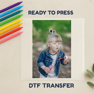 May include: A DTF transfer with the text "READY TO PRESS" and "DTF TRANSFER". The image shows a young child blowing bubbles. A set of rainbow-coloured crayons are on the left side of the image.