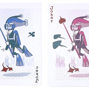 May include: Two playing cards featuring the Joker. One card has a blue and teal diver, the other a pink and purple diver. Both divers are holding a spear with a heart-shaped tip. The word "Joker" is printed on each card.