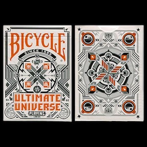 Puede incluir: Dos barajas de cartas Bicycle Ultimate Universe. La parte frontal de la baraja presenta la palabra "Bicycle" en naranja, con "Ultimate Universe" debajo. La parte posterior de la baraja tiene un dise&ntilde;o geom&eacute;trico en gris, naranja y blanco.