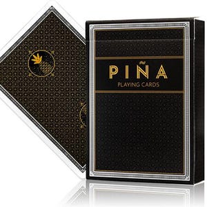 May include: A black playing card box and a single playing card. The box has the word "PIÑA" in gold lettering, with "PLAYING CARDS" below. The card backs have a gold pineapple design on a black background.