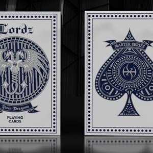 May include: Two decks of playing cards with a white background and a navy blue and silver design. One deck features a dragon design and the text "Twin Dragons Playing Cards". The other deck features a spade design and the text "Master Series".