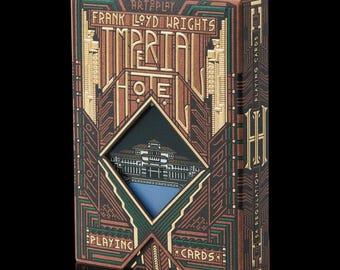 May include: A decorative playing card box featuring the words "Frank Lloyd Wright's Imperial Hotel Tokyo" in gold lettering. The box has a geometric design with brown, green, and gold accents. The box is labeled "Playing Cards".