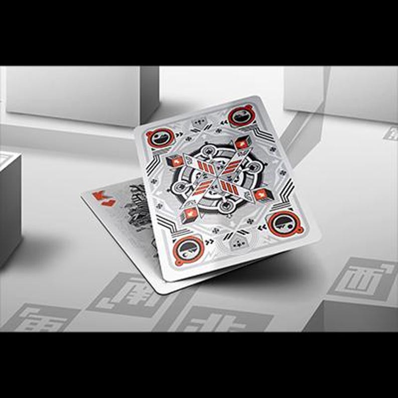 Puede incluir: Cartas de juego con un dise&ntilde;o geom&eacute;trico plateado y rojo en el reverso. Las cartas se muestran sobre una superficie blanca, con una est&eacute;tica minimalista. El dise&ntilde;o incluye elementos circulares y angulares.