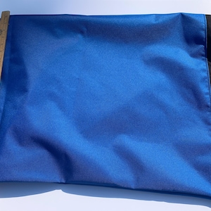 May include: A vibrant blue fabric item with a black border. A wooden ruler is placed along the side, showing measurements in inches. The fabric appears to be smooth and possibly satin or silk.