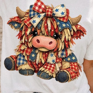 May include: A whimsical, patriotic cow design on a white t-shirt. The cow features a patchwork of red, white, and blue fabrics, including stars and gingham patterns. It has a pink nose, black eyes, and a matching bow.