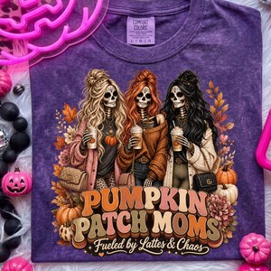 May include: Purple Comfort Colors t-shirt featuring a graphic of three skeleton women holding coffee cups, with the text "Pumpkin Patch Moms" and "Fueled by Lattes & Chaos". The design includes pumpkins and fall foliage.