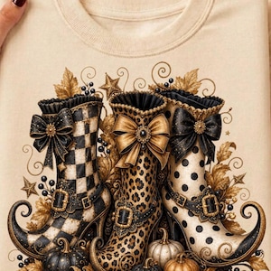 Può includere: Una felpa girocollo beige con una stampa grafica di tre stivali decorati con punta ricurva. Gli stivali presentano motivi a scacchi bianchi e neri, leopardati e a pois, ciascuno decorato con un grande fiocco, una fibbia e dettagli a foglia d'oro.
