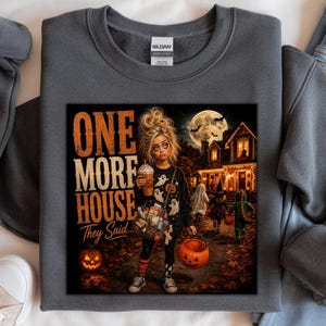 Puede incluir: Una sudadera gris oscuro de cuello redondo con un estampado gr&aacute;fico de una persona sosteniendo una bebida y un cubo de calabaza, rodeada de im&aacute;genes de Halloween. El texto dice ONE MORE HOUSE They Said. El dise&ntilde;o incluye una casa bajo la luna y ni&ntilde;os pidiendo dulces.