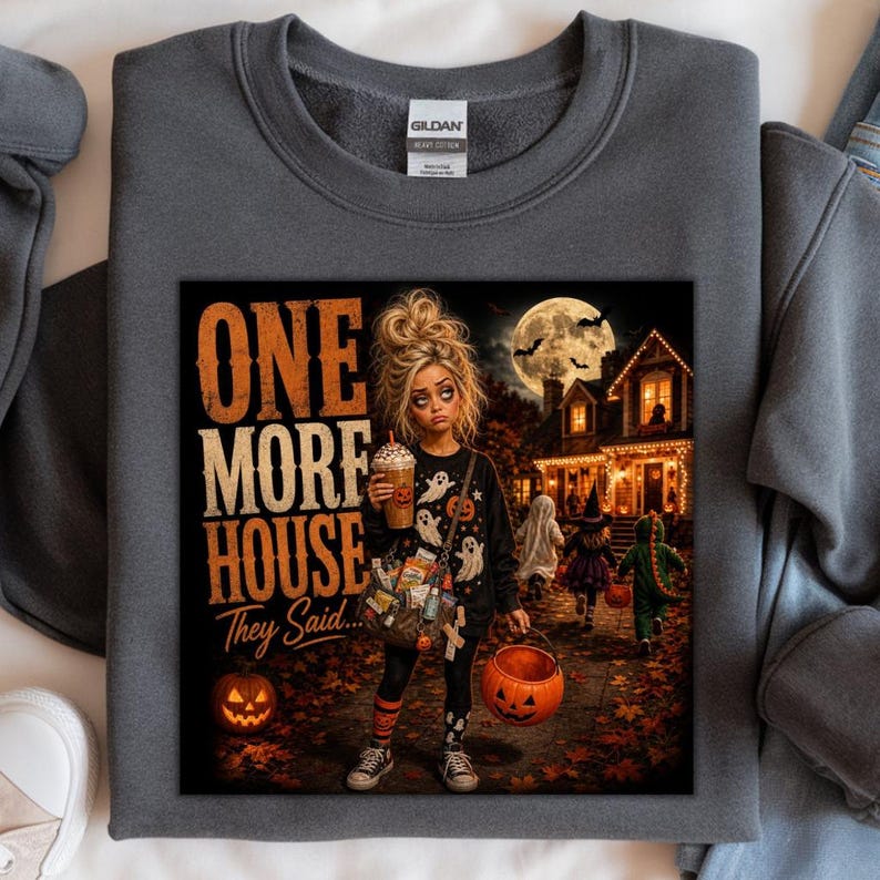 Puede incluir: Una sudadera gris oscuro de cuello redondo con un estampado gr&aacute;fico de una persona sosteniendo una bebida y un cubo de calabaza, rodeada de im&aacute;genes de Halloween. El texto dice ONE MORE HOUSE They Said. El dise&ntilde;o incluye una casa bajo la luna y ni&ntilde;os pidiendo dulces.