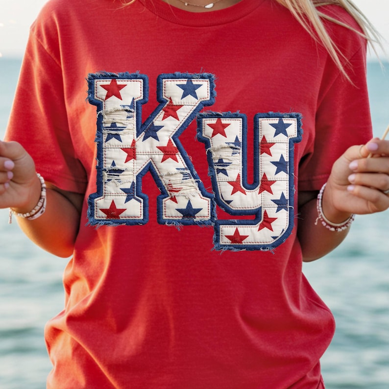 May include: Red t-shirt with the letters "KY" in a distressed design. The letters are filled with red and blue stars on a white background, outlined with a blue denim-like trim.
