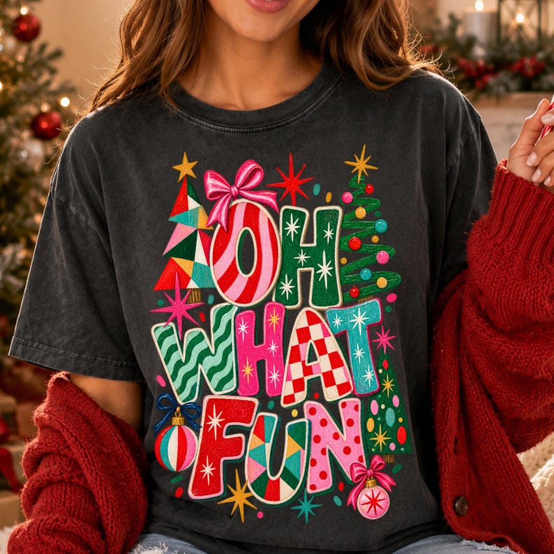 K&ouml;nnte beinhalten: Ein anthrazitfarbenes Kurzarm-T-Shirt mit einer bunten Weihnachtsgrafik und dem Schriftzug OH WHAT FUN. Das Design zeigt stilisierte Weihnachtsb&auml;ume, rosa Schleifen, Christbaumkugeln und Sternmotive in den Farben Rot, Gr&uuml;n, Pink und Blau.