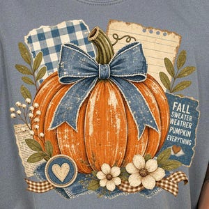 Könnte beinhalten: Hellblaues T-Shirt mit einem orangefarbenen Kürbis-Design und einer blauen Schleife. Das Design umfasst florale Elemente, ein Herz und den Text "FALL SWEATER WEATHER PUMPKIN EVERYTHING" auf blauem Hintergrund.