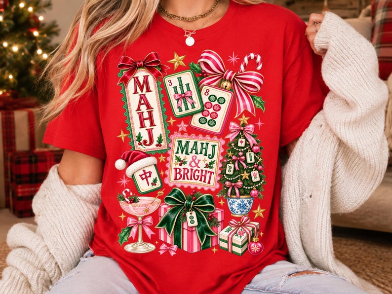 K&ouml;nnte beinhalten: Ein leuchtend rotes T-Shirt mit einer festlichen Grafik aus Mahjong-Steinen, einem mit Mahjong-Steinen geschm&uuml;ckten Weihnachtsbaum, Geschenken, einem Cocktailglas und Schleifen. Der Text lautet "MAHJ" und "MAHJ & BRIGHT" in Rot und Gr&uuml;n.