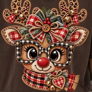 Può includere: Una t-shirt grigio scuro con la grafica di una renna che indossa occhiali a scacchi bianchi e neri. La renna ha corna con stampa leopardata con campanellini dorati, un fiocco scozzese rosso con un bottone marrone, un naso rosso e una sciarpa scozzese.