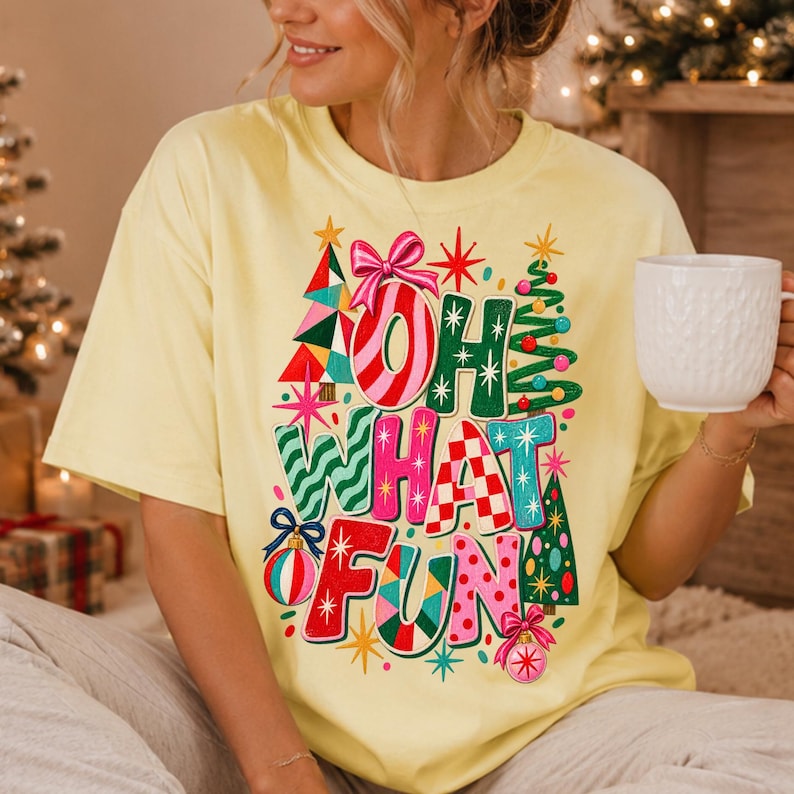 K&ouml;nnte beinhalten: Ein hellgelbes T-Shirt mit kurzen &Auml;rmeln und einem farbenfrohen Grafikdruck mit dem Text "OH WHAT FUN". Das Design zeigt stilisierte Weihnachtsb&auml;ume, eine rosa Schleife und verschiedene Ornamente in Rot, Gr&uuml;n, Blau und Rosa mit Sternakzenten.