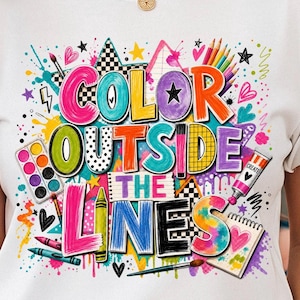 May include: A white t-shirt featuring a colorful graphic with the text "COLOR OUTSIDE THE LINES". The design includes illustrations of paintbrushes, a watercolor palette, crayons, a paint tube, and a sketchbook, surrounded by paint splatters.