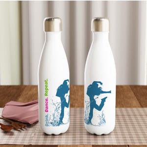 Pode incluir: Duas garrafas de água brancas com tampas prateadas. Cada uma apresenta uma silhueta azul de uma dançarina com gráficos de respingos de água. O texto "Drink. Dance. Repeat." é impresso verticalmente em uma garrafa.