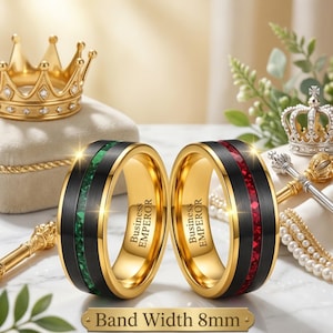 Könnte beinhalten: Zwei Ringe mit einer Bandbreite von 8 mm, mit einer schwarzen Mitteleinlage mit grüner oder roter Textur aus zerkleinertem Stein, flankiert von goldenen Rändern. Die Innenseite jedes Rings ist mit dem Text Business EMPEROR graviert.