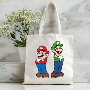 Pode incluir: Uma sacola de lona branca com ilustra&ccedil;&otilde;es de desenhos animados de Mario e Luigi. Mario est&aacute; usando um chap&eacute;u e camisa vermelhos com macac&atilde;o azul, enquanto Luigi est&aacute; com um chap&eacute;u e camisa verdes com macac&atilde;o azul. Ambos os personagens est&atilde;o com os bra&ccedil;os cruzados.