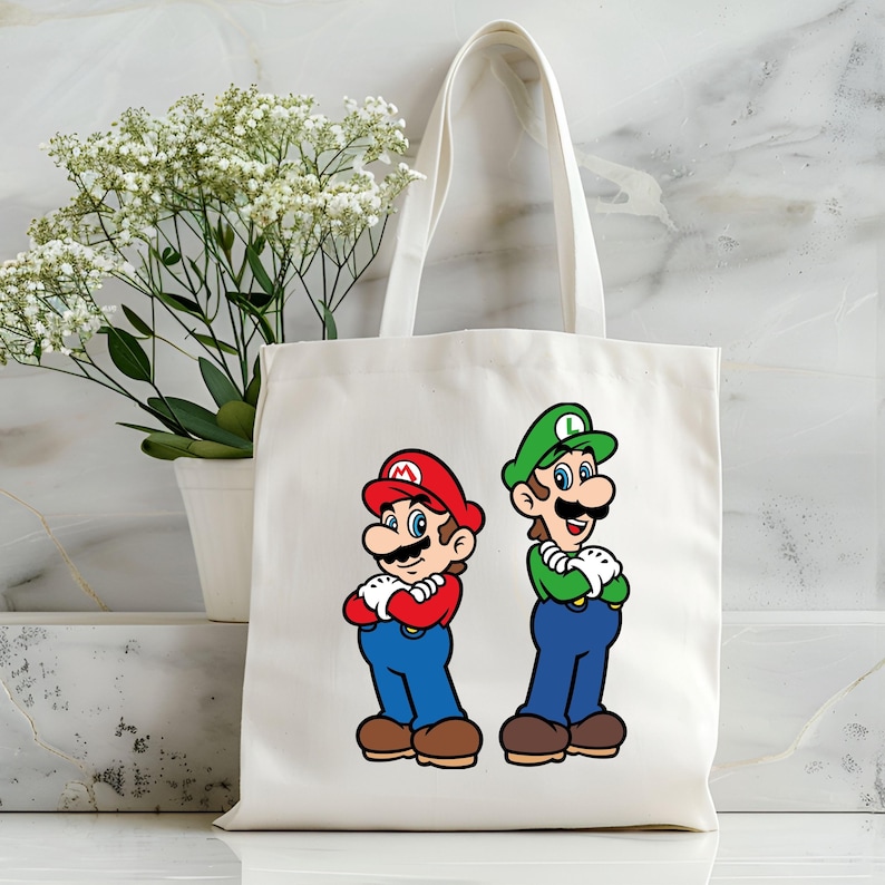 Pode incluir: Uma sacola de lona branca com ilustra&ccedil;&otilde;es de desenhos animados de Mario e Luigi. Mario est&aacute; usando um chap&eacute;u e camisa vermelhos com macac&atilde;o azul, enquanto Luigi est&aacute; com um chap&eacute;u e camisa verdes com macac&atilde;o azul. Ambos os personagens est&atilde;o com os bra&ccedil;os cruzados.