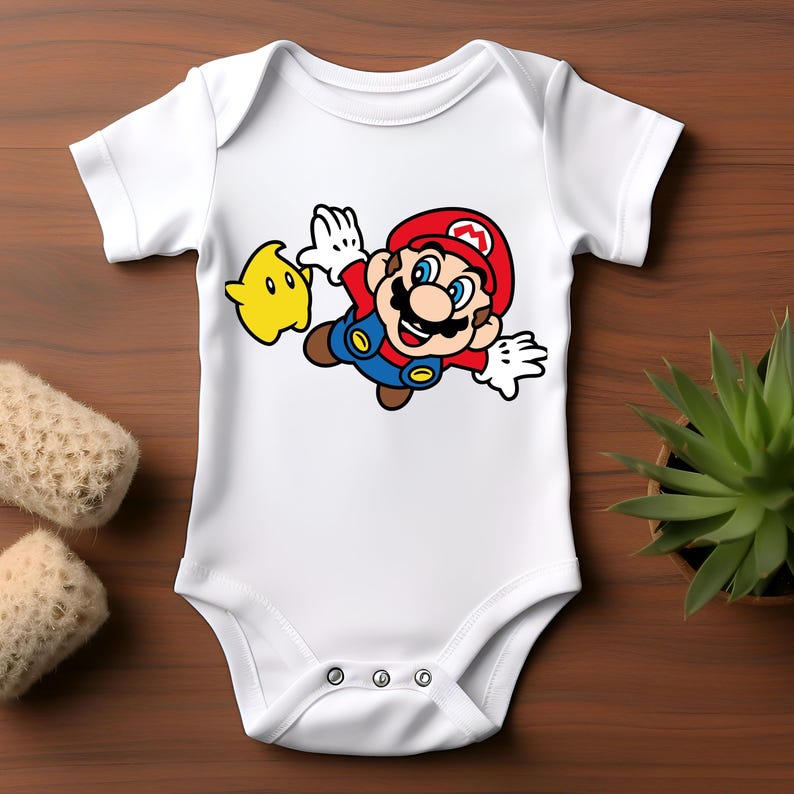 Pode incluir: Body de beb&eacute; branco com um gr&aacute;fico colorido do Mario do videogame Super Mario Bros. Mario &eacute; retratado no ar com uma estrela amarela. O body tem um fecho de press&atilde;o na parte inferior.