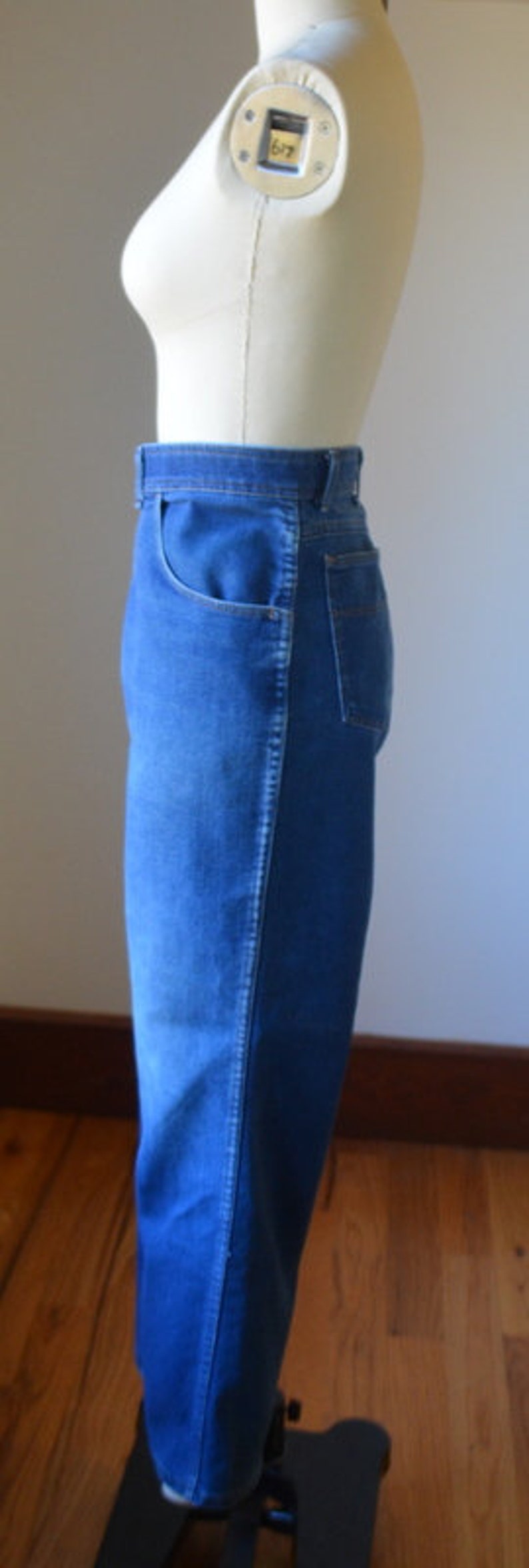 May include: Blue denim jeans with a classic five-pocket design. The jeans are displayed on a mannequin, showcasing the fit and style. The jeans have a straight leg and a medium wash.