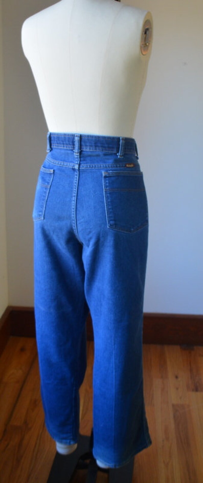 May include: Blue denim jeans with a high waist and straight leg. The jeans have pockets on the front and back, and are displayed on a mannequin. The jeans are a medium wash and have a classic, timeless style.