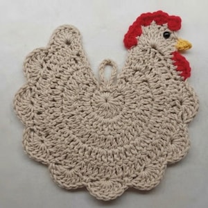 May include: A beige crochet potholder shaped like a chicken, featuring a red comb and wattle, a yellow beak, and a small black eye. The body is crafted with a scalloped edge design and includes a small loop at the top for hanging purposes.
