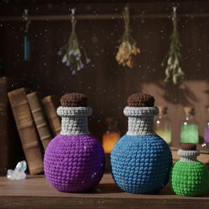 Puede incluir: Tres botellas de poción de ganchillo en morado, azul y verde, con tapones de corcho marrón. Las botellas tienen detalles grises y están sobre una estantería de madera. Hierbas secas cuelgan en el fondo, sugiriendo un tema místico.