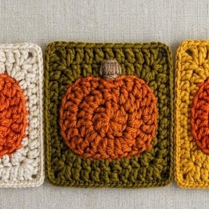 May include: Three square crochet motifs featuring a central orange pumpkin design with a small brown stem. The pumpkins are centered on backgrounds of cream, olive green, and mustard yellow yarn, each worked in a classic granny square pattern.