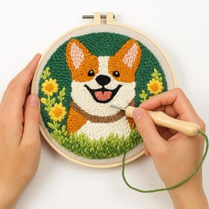 Könnte beinhalten: Stickrahmen-Kunst mit einem lächelnden Corgi-Hund, orange-weißem Fell und einem braunen Halsband. Der Hintergrund ist grün mit gelben Blumen und grünem Gras. Eine Person verwendet eine Punchnadel, um die Stickerei zu erstellen.