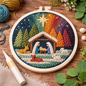 Op de afbeelding: Een kleurrijke, handgemaakte borduurring met een kerststal. Het ontwerp omvat een stal, figuren, dieren en een regenbooghemel met een ster. De borduursels zijn in een houten ring geplaatst, met garen en gereedschap zichtbaar.