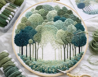 May include: An embroidery hoop featuring a detailed forest scene with trees in various shades of green. The artwork is surrounded by spools of green thread, a needle, and a pair of gold scissors. The embroidery is on a white background.