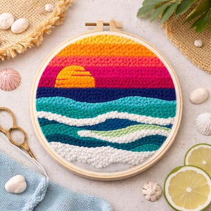 Könnte beinhalten: Ein farbenfrohes, handgefertigtes Stickrahmen-Kunstwerk, das einen Sonnenuntergang über dem Meer darstellt. Das Design zeigt einen Himmel mit Farbverlauf in Orange, Rosa und Lila, mit einer gelben Sonne, die über blauen und türkisfarbenen Wellen untergeht. Das Werk ist in einem Holzrahmen gefasst.