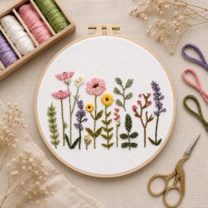May include: A circular embroidery hoop with a hand-stitched floral design in pink, yellow, purple, and green. The image also shows a wooden thread organiser and gold-coloured scissors.