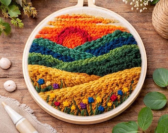 May include: A colorful, handcrafted embroidery hoop art piece depicting a sunset over rolling hills. The artwork features a vibrant palette of orange, red, green, blue, and yellow, with detailed textures and small floral accents. The piece is set in a wooden hoop.