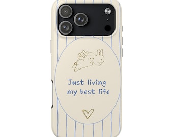 May include: A phone case with a cream-colored background and blue vertical stripes. The case features a circular design with two sketched rabbits and the text "Just living my best life" in blue, along with a small gold heart.