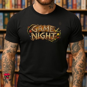 May include: Black t-shirt featuring the text "GAME NIGHT" in a distressed, vintage style. The design uses a brown and gold colour scheme with decorative elements. A fun shirt for game enthusiasts.