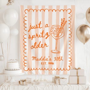 May include: A peach and white striped banner with the text "just a spritz older" and "Maddie's 30th EST. 1996" in orange. The banner features a drawing of a cocktail. White balloons, a cake, and gifts are in the scene.