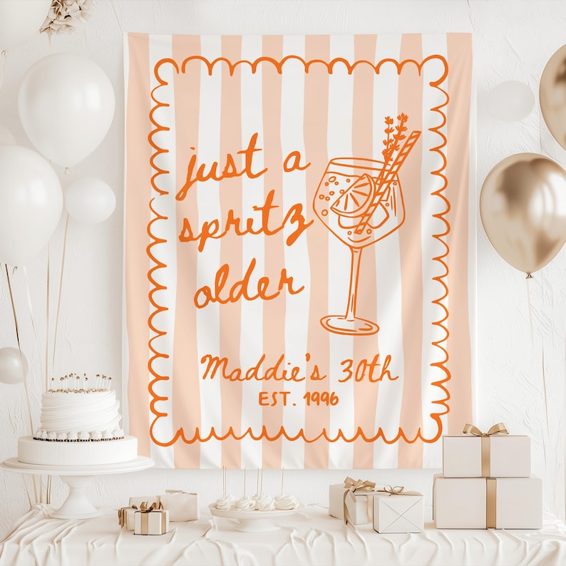 May include: A peach and white striped banner with the text "just a spritz older" and "Maddie's 30th EST. 1996" in orange. The banner features a drawing of a cocktail. White balloons, a cake, and gifts are in the scene.