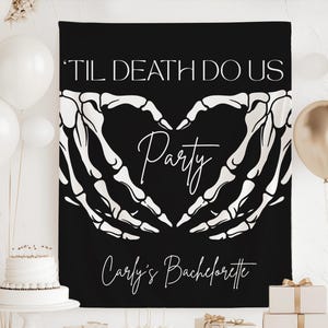 May include: A black rectangular fabric banner featuring white skeleton hands forming a heart shape in the center. The text reads 'TIL DEATH DO US' in a bold sans-serif font, 'Party' in a script font, and 'Carly's Bachelorette' in a script font.