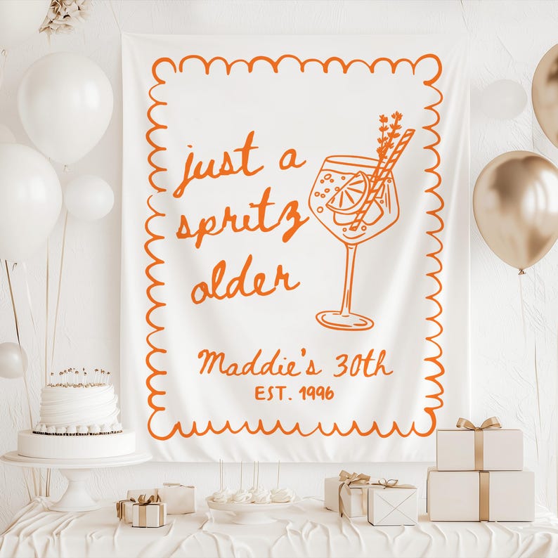 May include: White banner with orange text and illustration for a 30th birthday. The banner reads "just a spritz older" with a cocktail illustration and "Maddie's 30th EST. 1996". The scene includes balloons, a cake, and gifts.